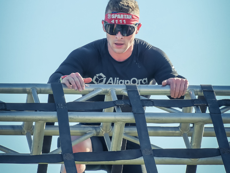 Learn what a Spartan race can teach us about an organizational race - a competitor climbs over an obstacle