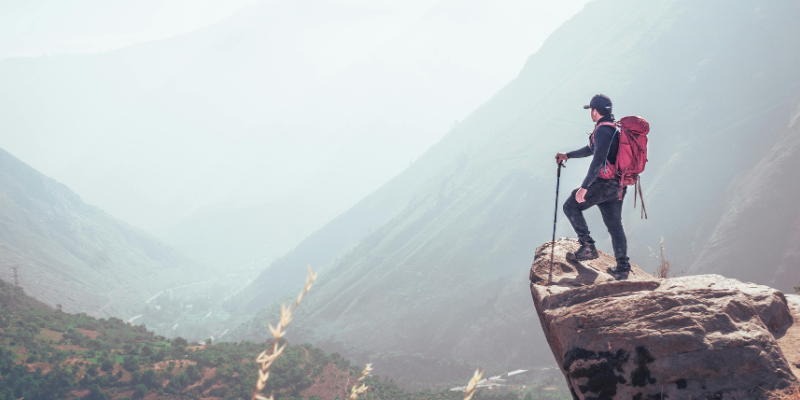 An agile hiker looks into a cloudy valley