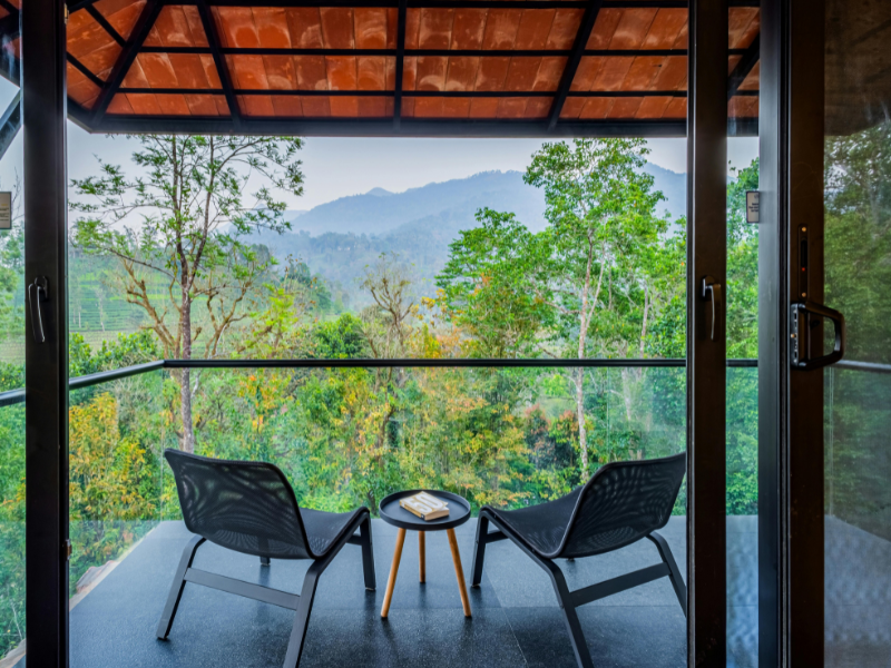 Two chairs on a balcony overlooking a forest.