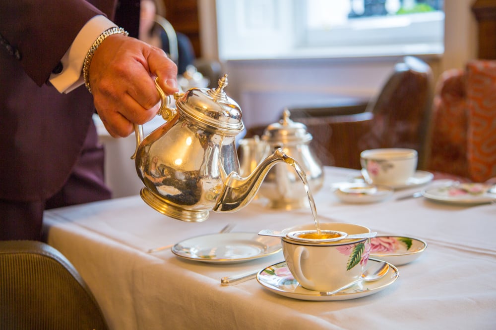 A man pouring tea in an English tea service.