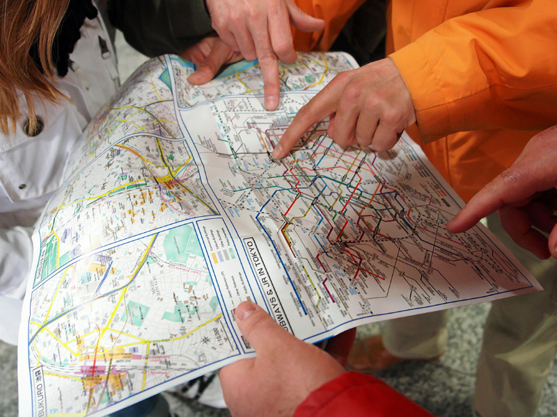 Multiple fingers pointing to different places on a map as a way to the price of another priority.